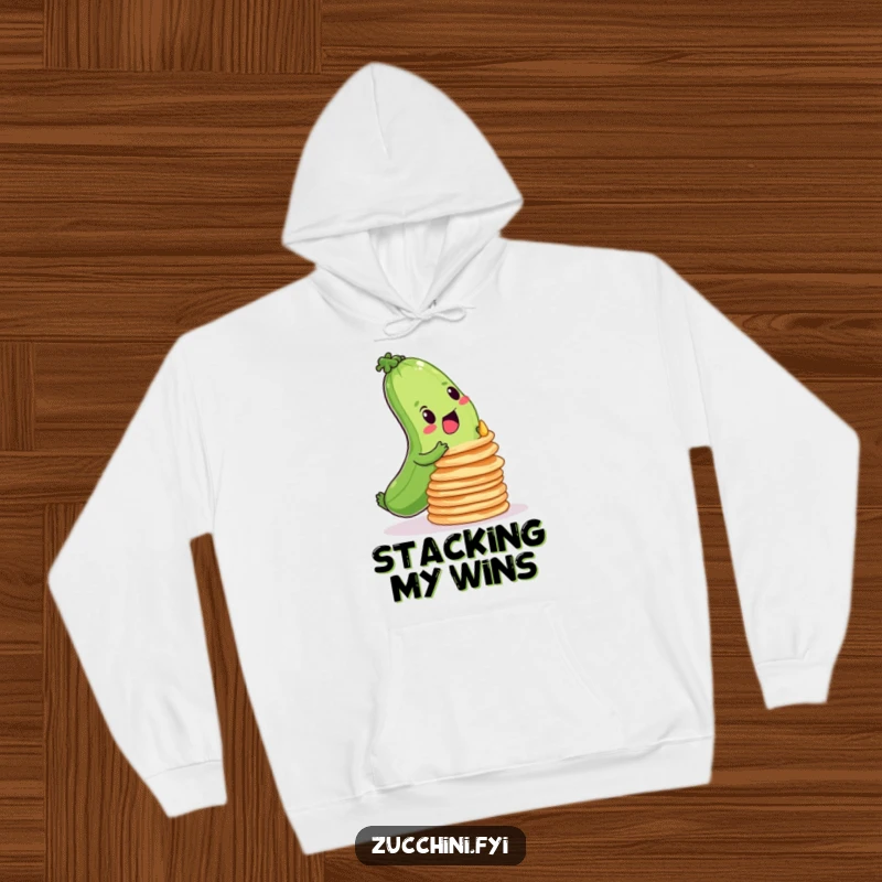 Funny hoodie depicting a focused zucchini attempting to balance a tall stack of wobbly pancakes, symbolizing effort.